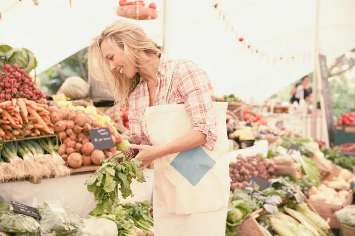 midlife woman enjoying fresh local produce at a farmer's market